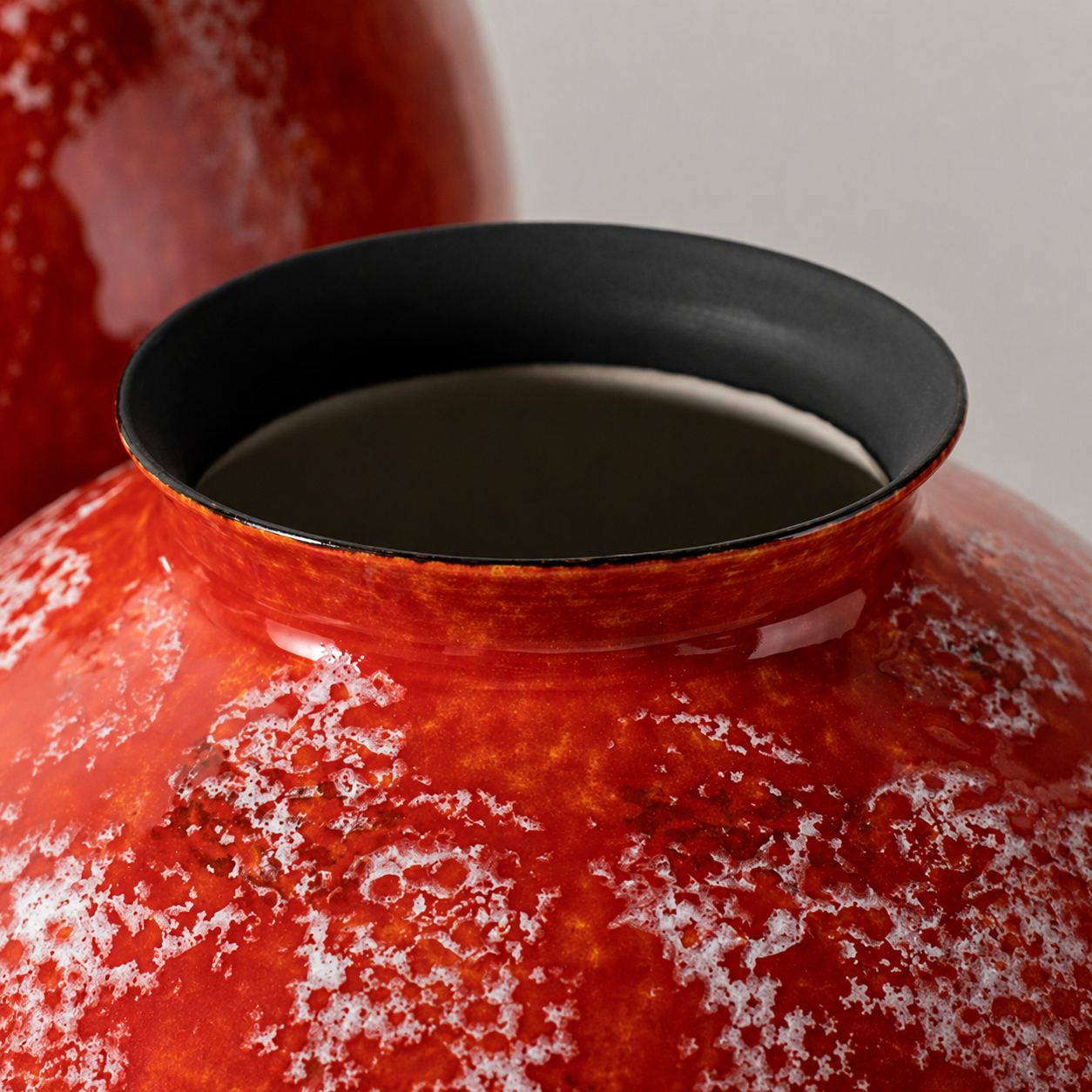Close up of black rim and opening on glossy orange ceramic vase