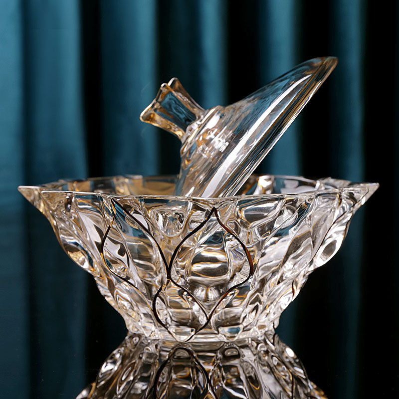 Gold accented faceted glass bowl with lid lifted against a teal background