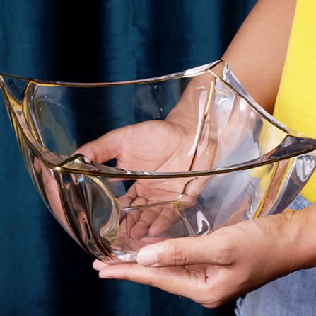 Side view of gold rimmed wavy glass bowl being held by hand