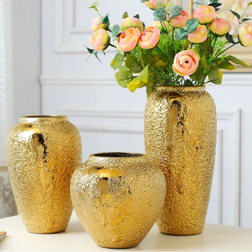 Textured gold tone ceramic vase collection displayed with peach flowers