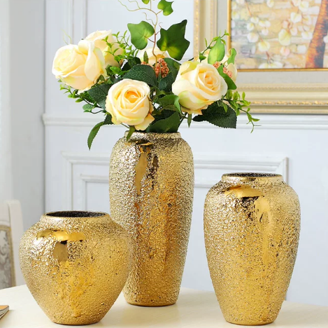 Gold tone ceramic vases styled with white and yellow floral arrangement