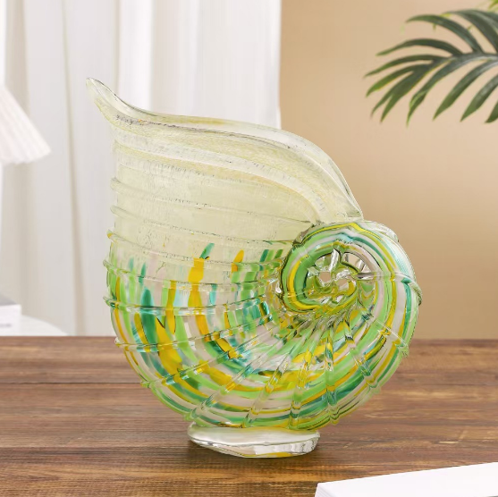 Sculptural nautilus shell art glass vase displayed on a wooden table
