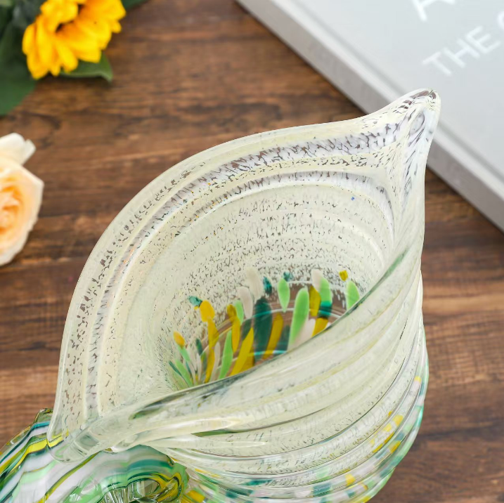 Close up of nautilus shell art glass vase showing ribbed glass texture and green amber color