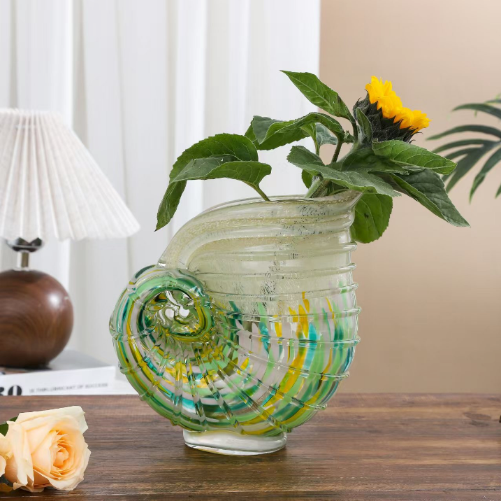 Green and amber art glass shell vase with fresh greenery in modern home decor