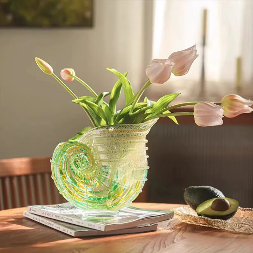 Green and amber nautilus shell vase with tulips on a sunlit table