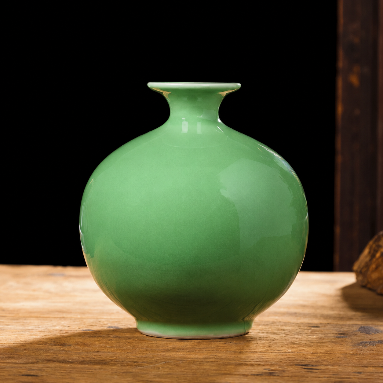 Round green ceramic vase with short neck on wooden table