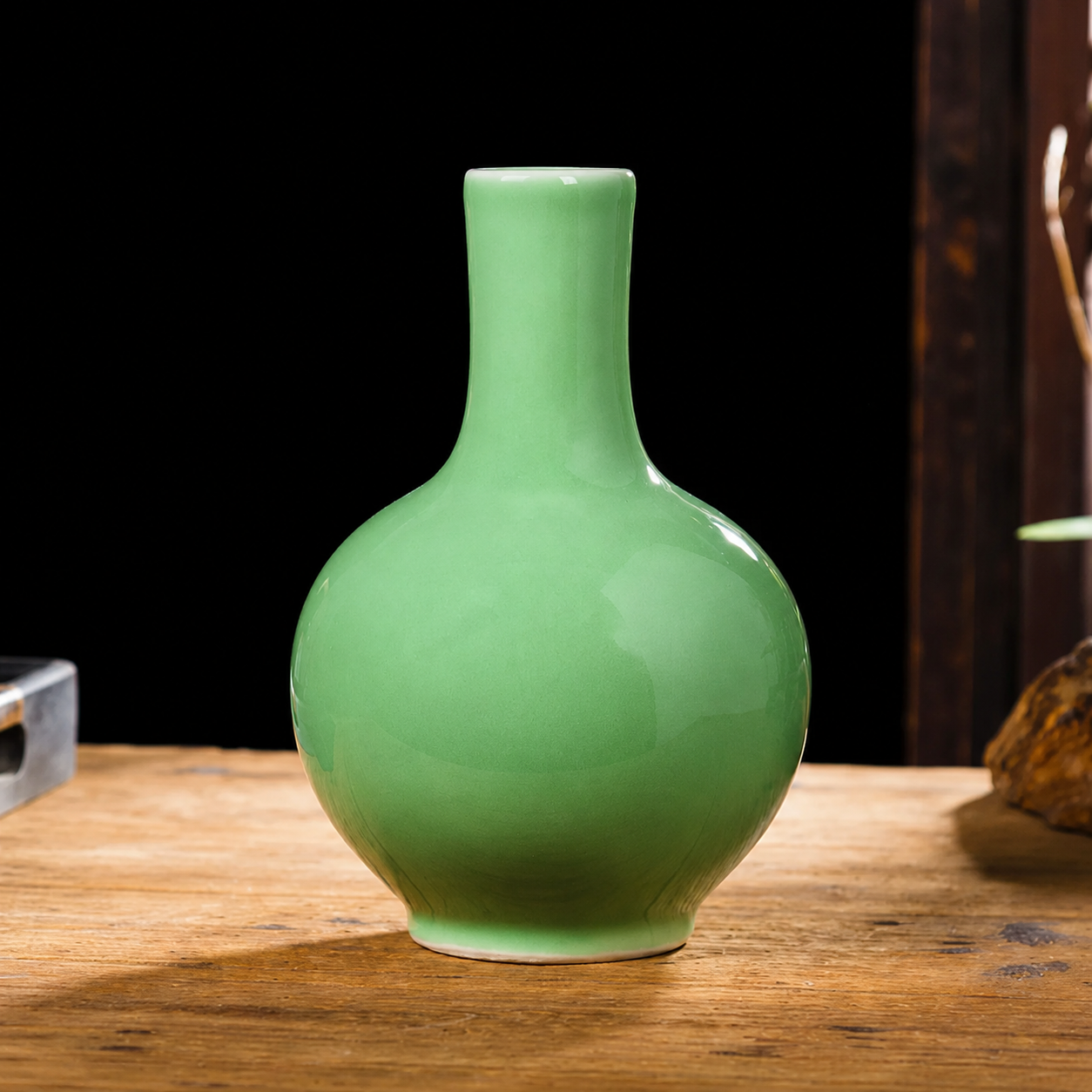 Green ceramic long neck round vase on wooden table