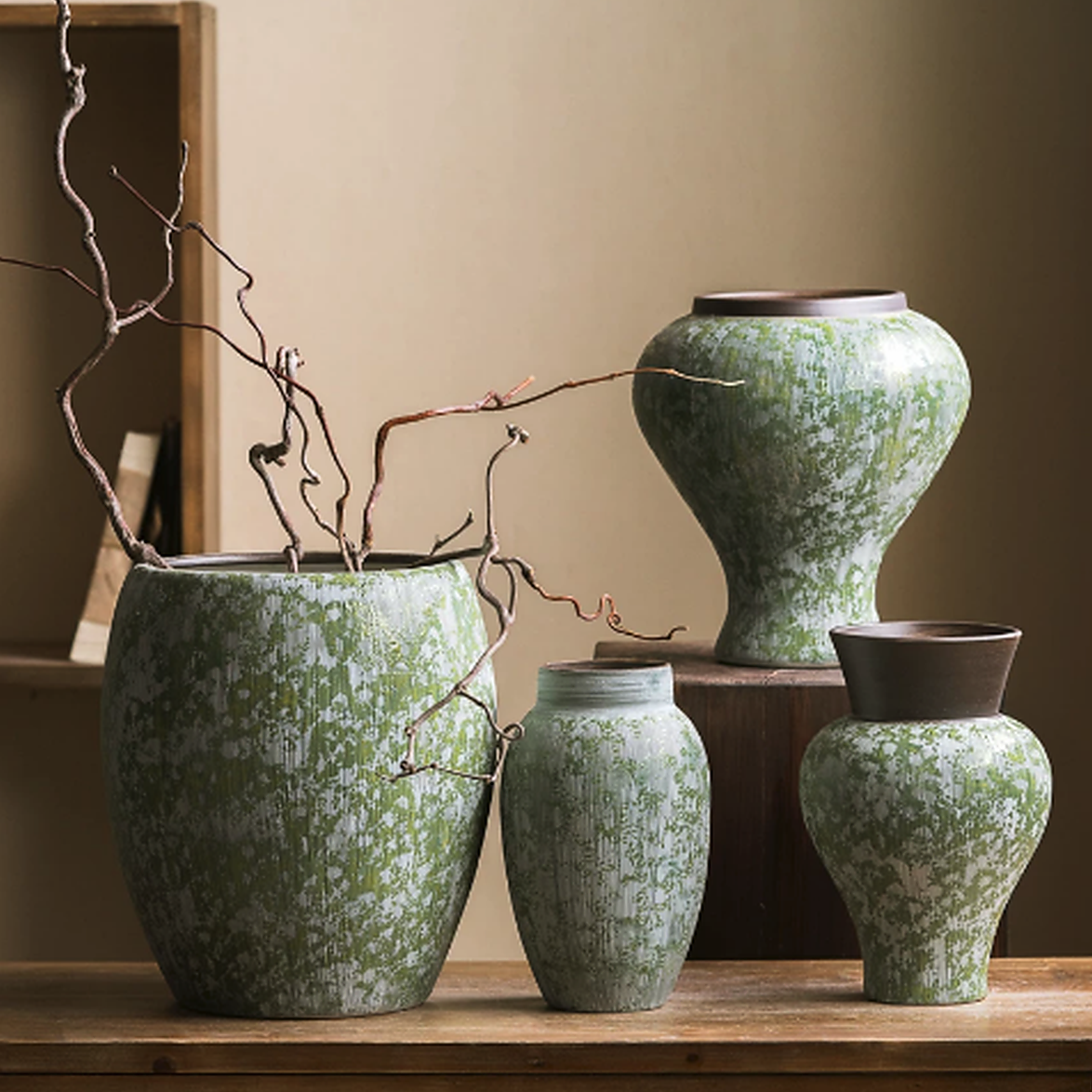 Green speckled ceramic vases displayed on wooden table with rustic branch styling