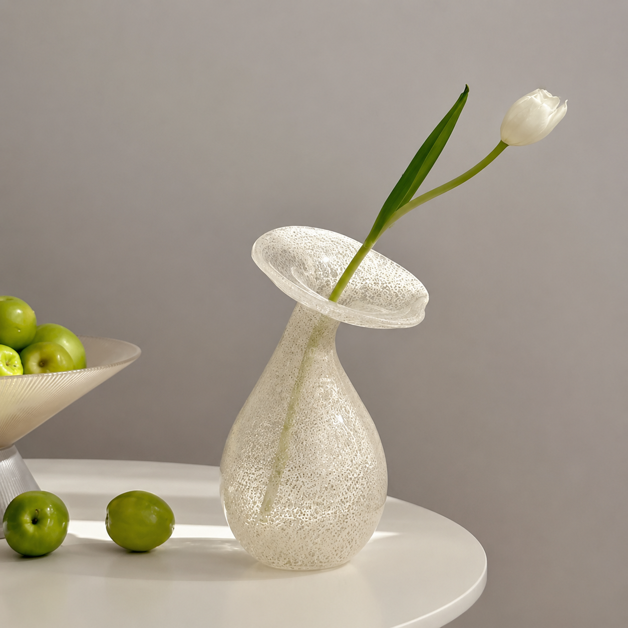 Hand-blown speckled glass bud vase styled with a single white tulip and green apples