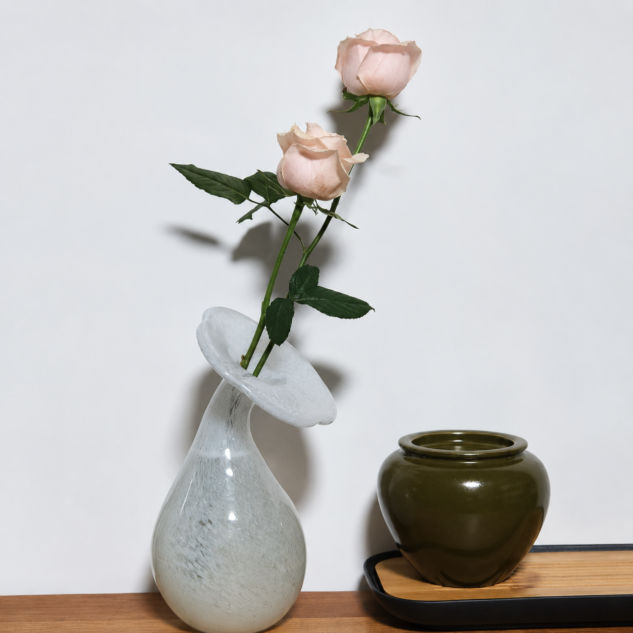 Pale hand-blown glass bud vase styled with blush roses and ceramic decor