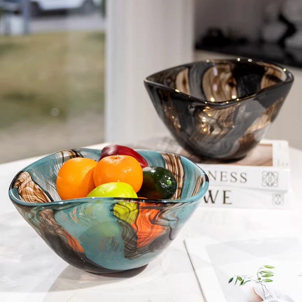 Art glass centerpiece bowl with fruit styled on books beside a dark decorative bowl