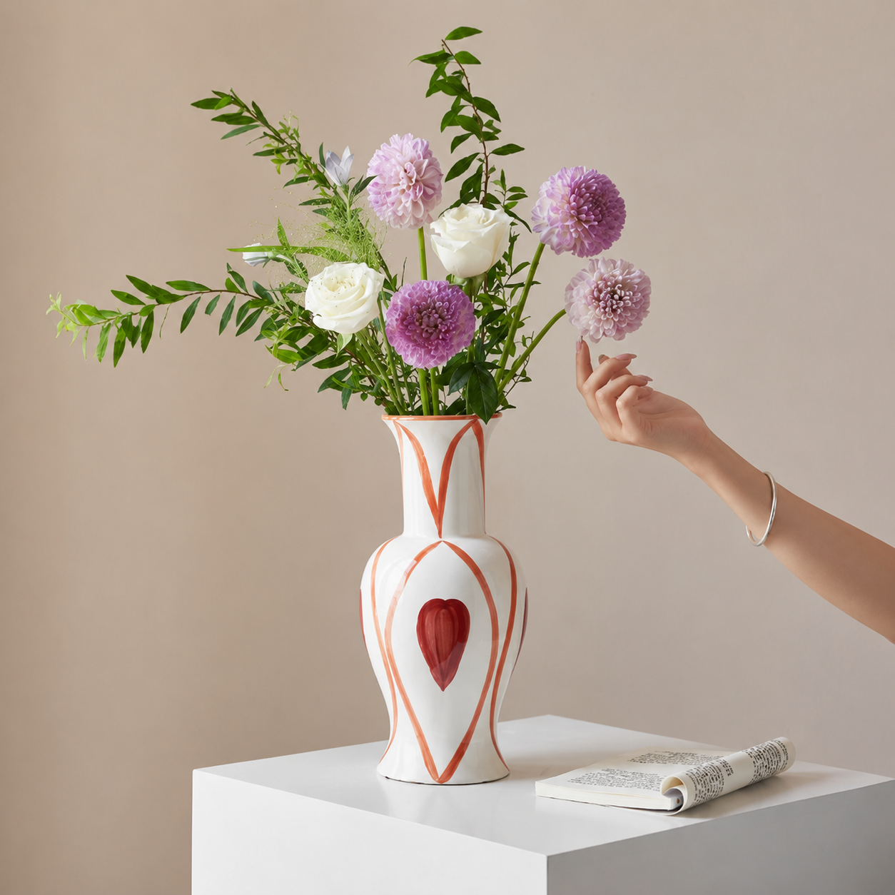 White and red hand painted ceramic flower vase with purple and white floral arrangement on pedestal