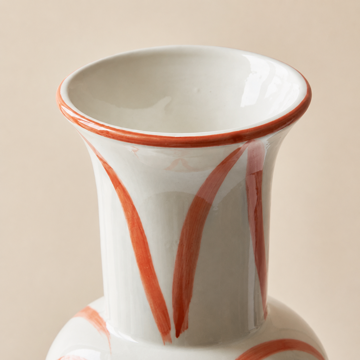 Close up of glossy ceramic vase rim with red hand painted brushstroke pattern