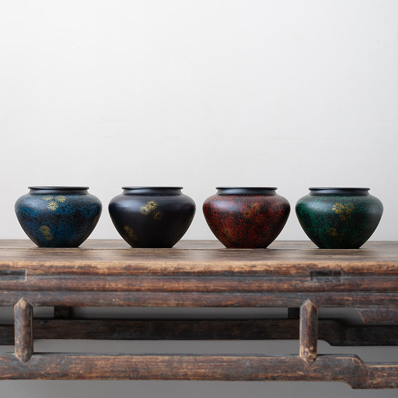 Four jewel toned iron tea ritual bowls displayed together on a wooden table