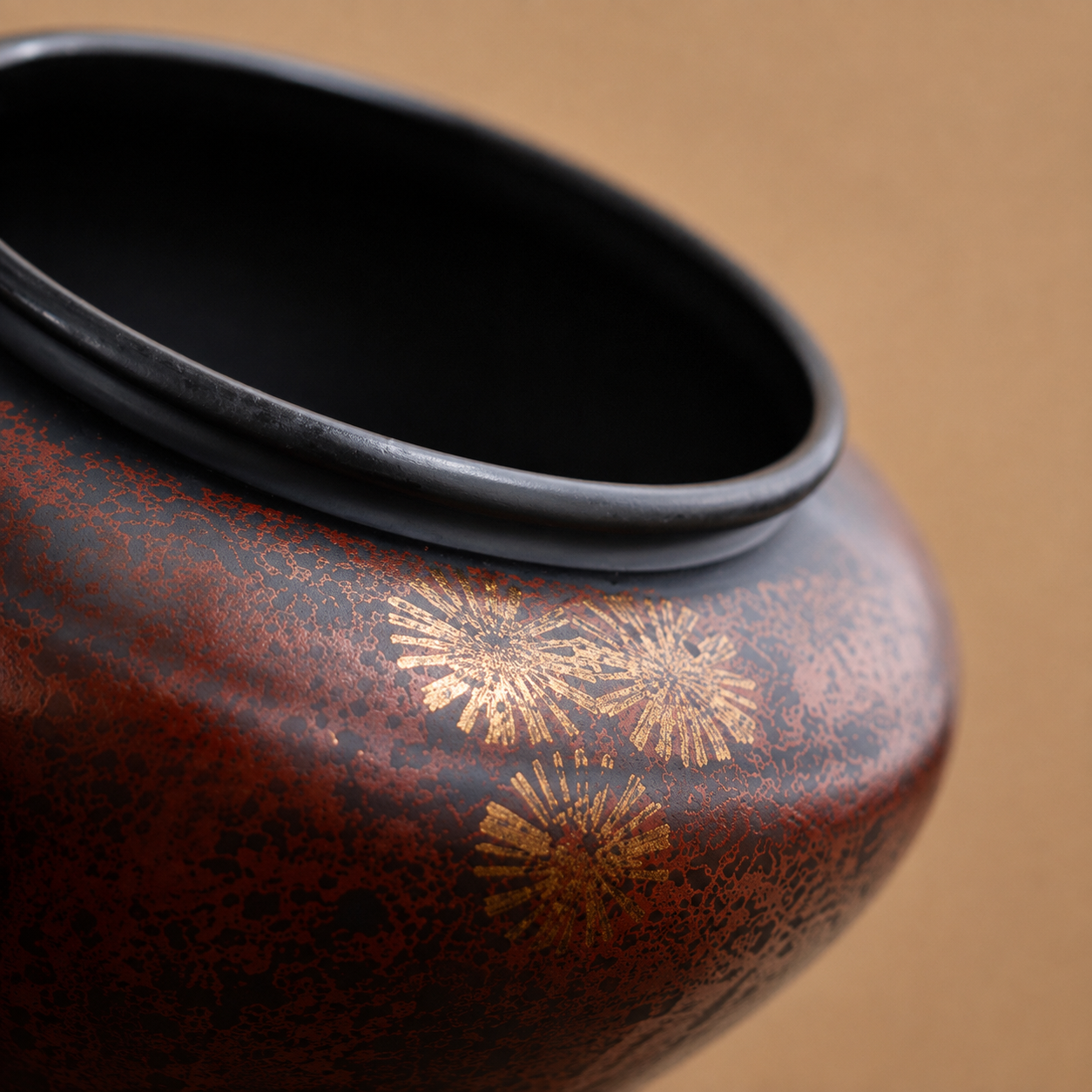 Close up of Burnished Maroon iron tea ritual bowl with gold starburst detailing