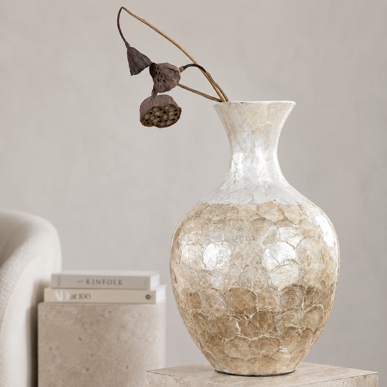 Shell inlay ceramic vase with dried lotus stems in minimalist neutral interior