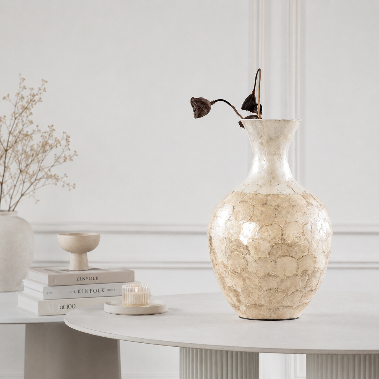 Handcrafted shell inlay ceramic vase styled on white table with dried botanical stems