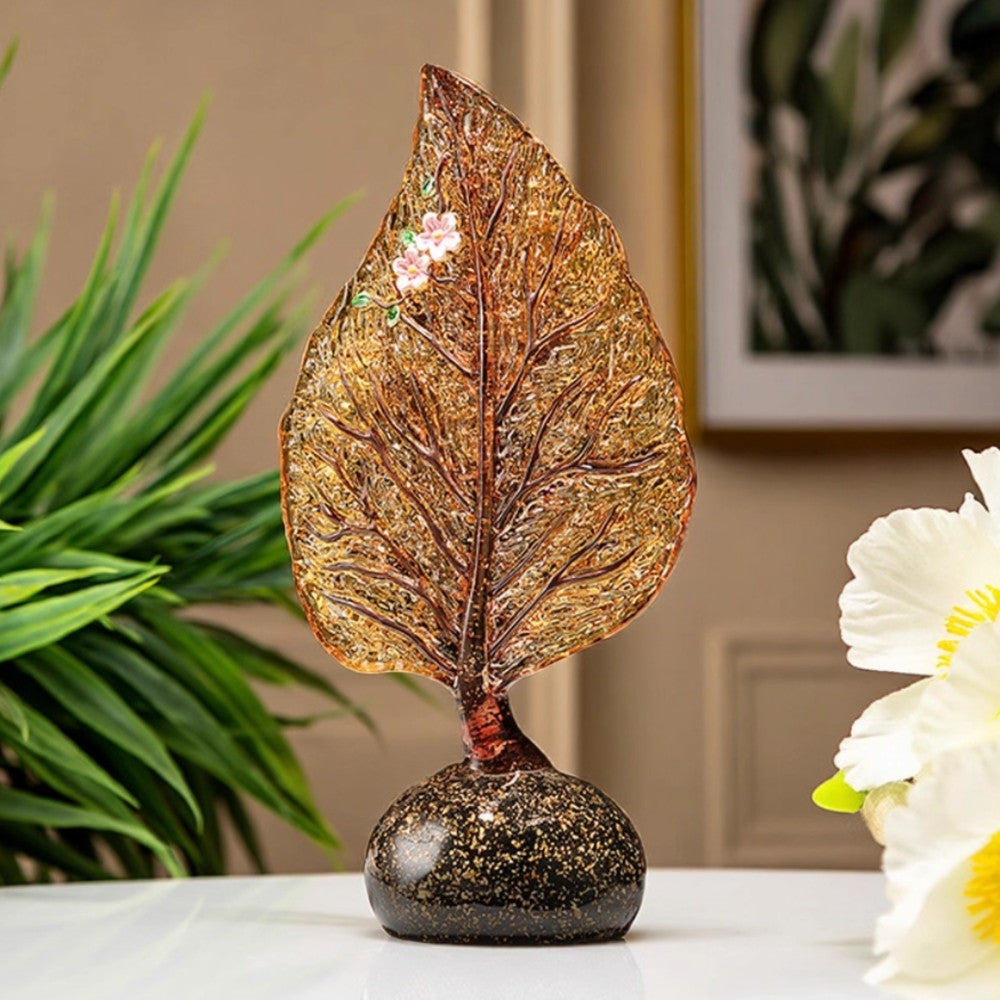 Decorative amber glass leaf sculpture styled with floral background on table
