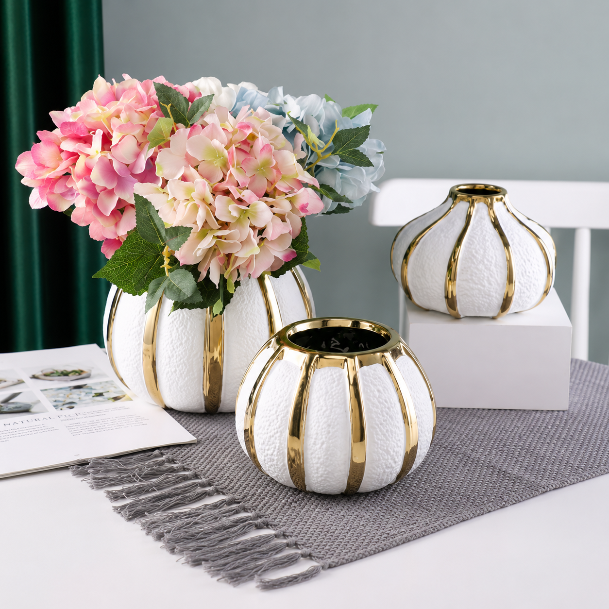 White and gold ceramic vases styled with pink hydrangeas on a refined tabletop display
