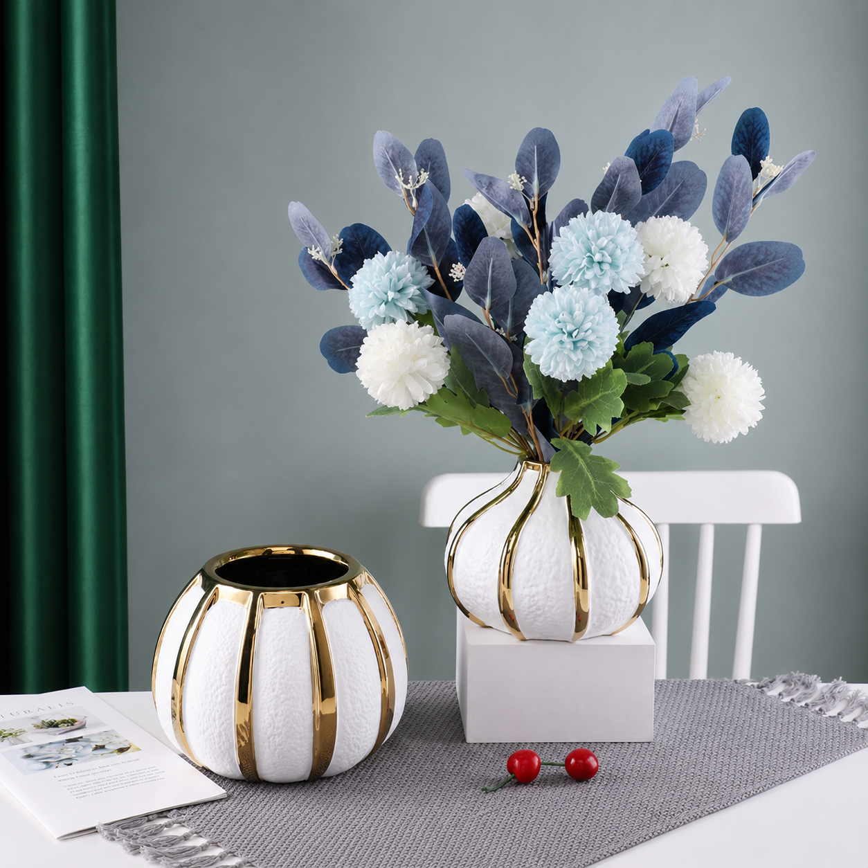 Luxury white ceramic vase with gold accents styled with blue and white flowers beside matching round vase