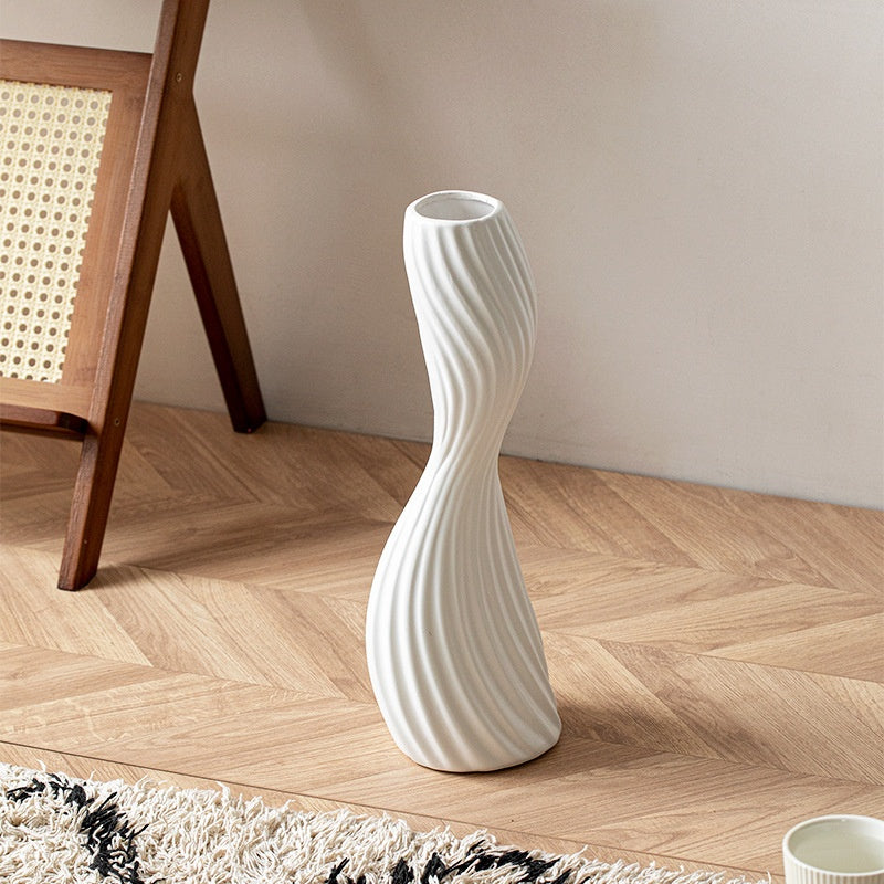 White ribbed ceramic twist floor vase in a minimalist living room