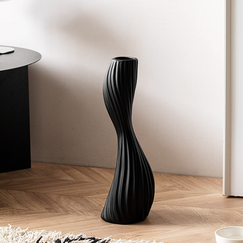 Black ribbed ceramic twist floor vase displayed on wooden floor as sculptural modern home decor