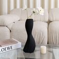 Black minimalist ribbed ceramic twist vase with white flowers on glass coffee table