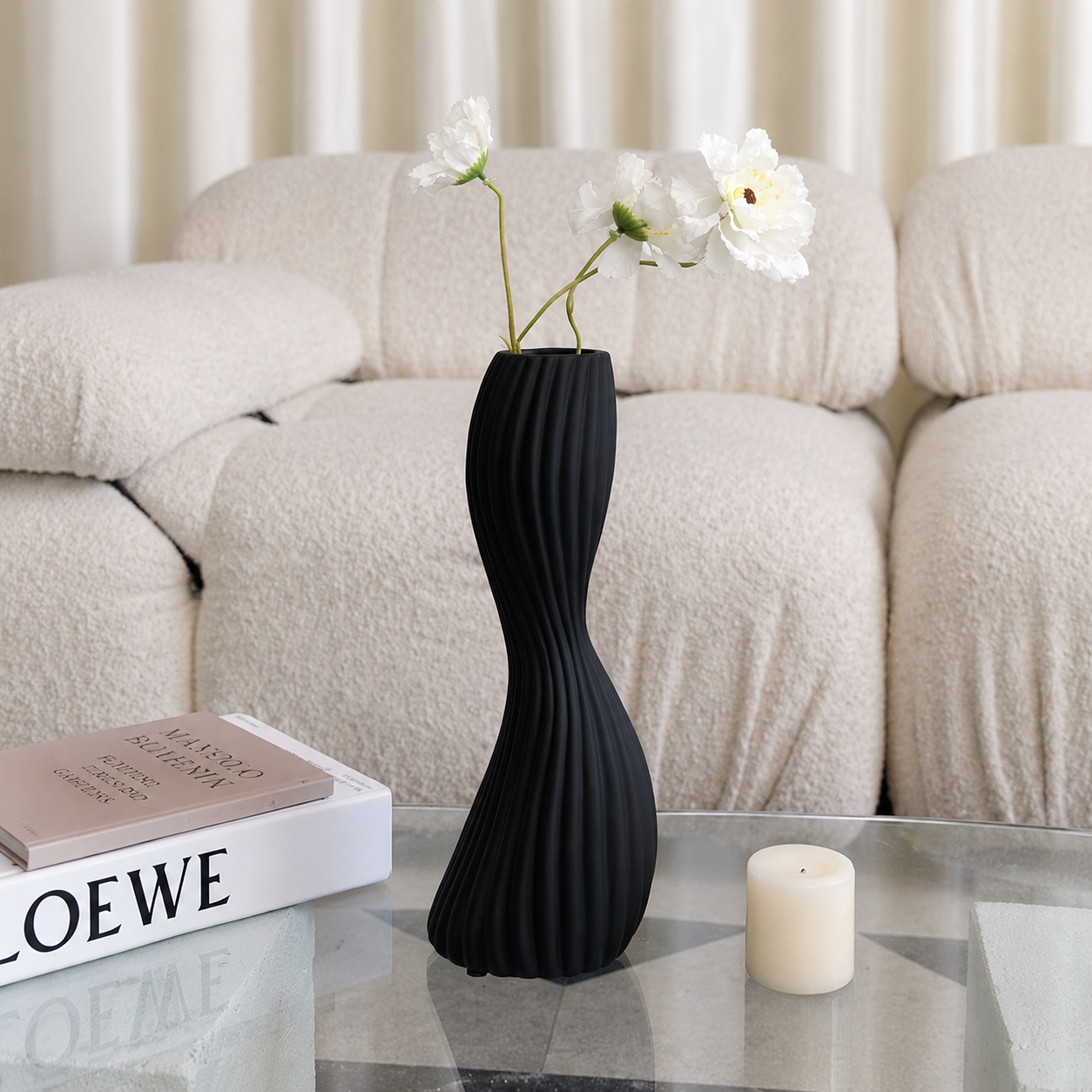 Black minimalist ribbed ceramic twist vase with white flowers on glass coffee table