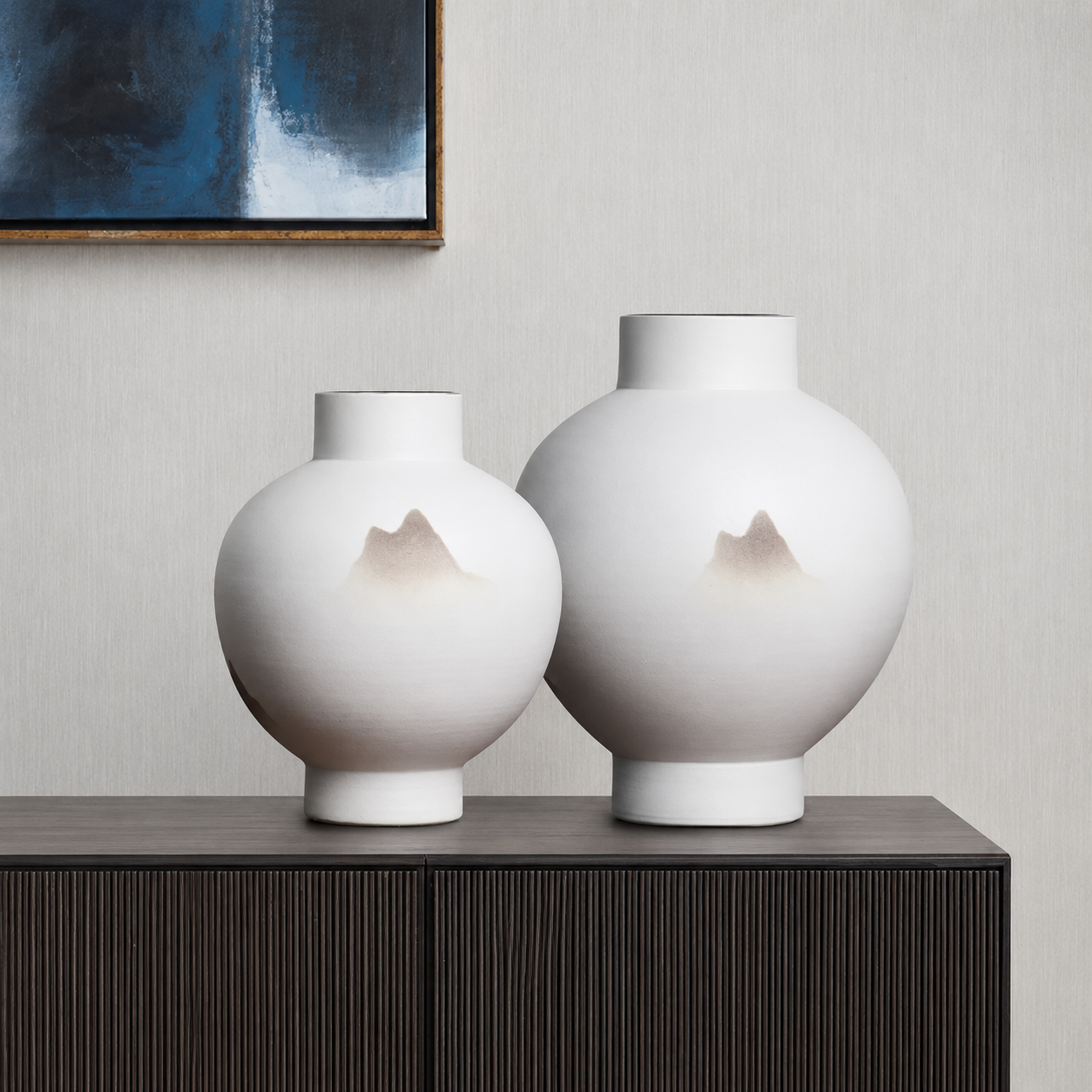White ceramic mountain vase set styled on a modern console with abstract wall art