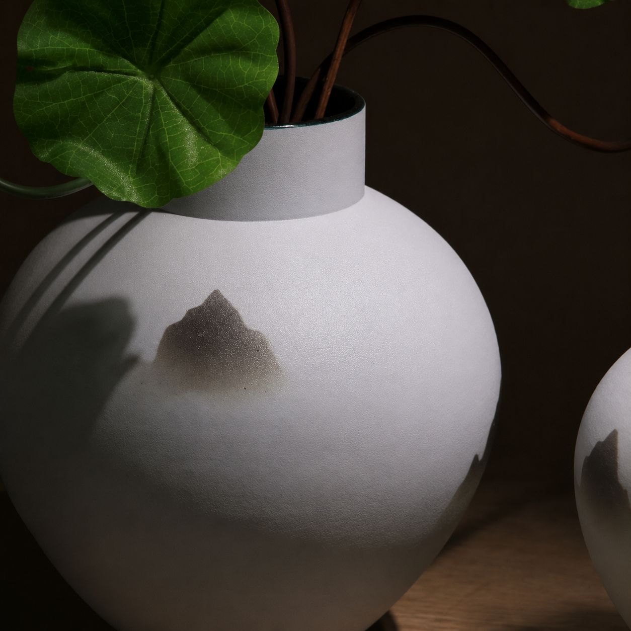Close-up of matte white ceramic mountain vase with subtle ink-wash landscape motif