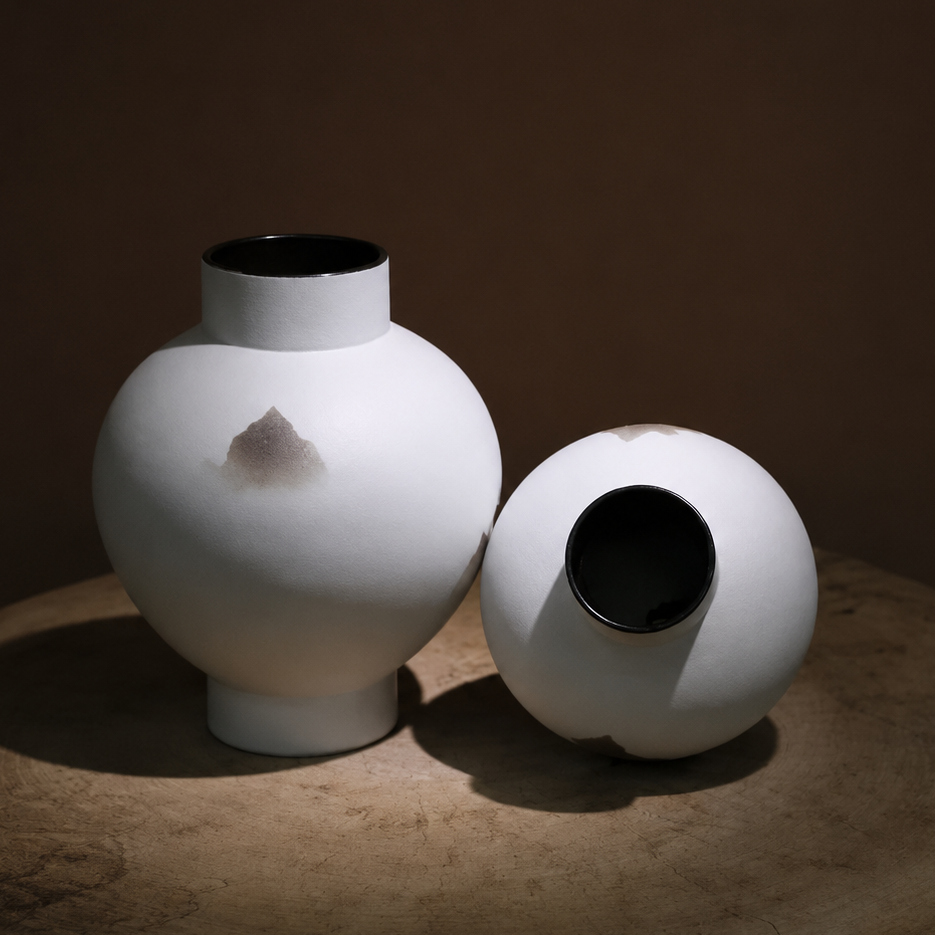 White ceramic mountain vases styled upright and tilted on a rustic wooden table