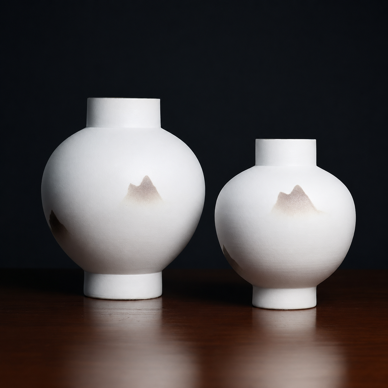 Medium and large white ceramic mountain vases against a dark background