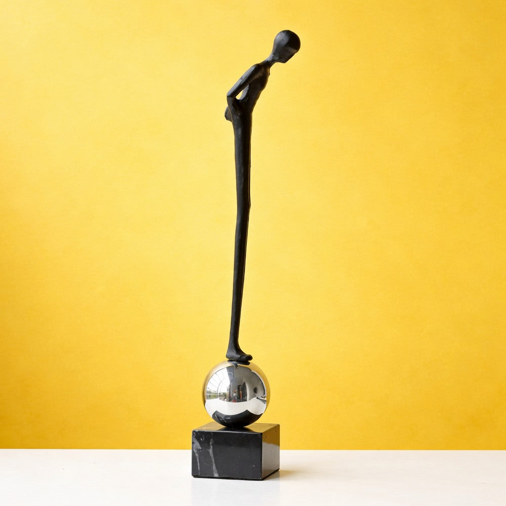 Black standing abstract alloy sculpture balancing on a chrome sphere and black base