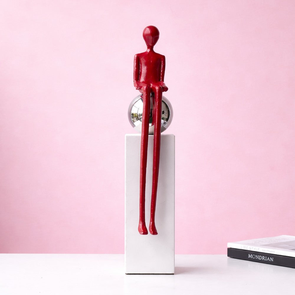 Burgundy sitting abstract figure sculpture on white pedestal against a soft pink background