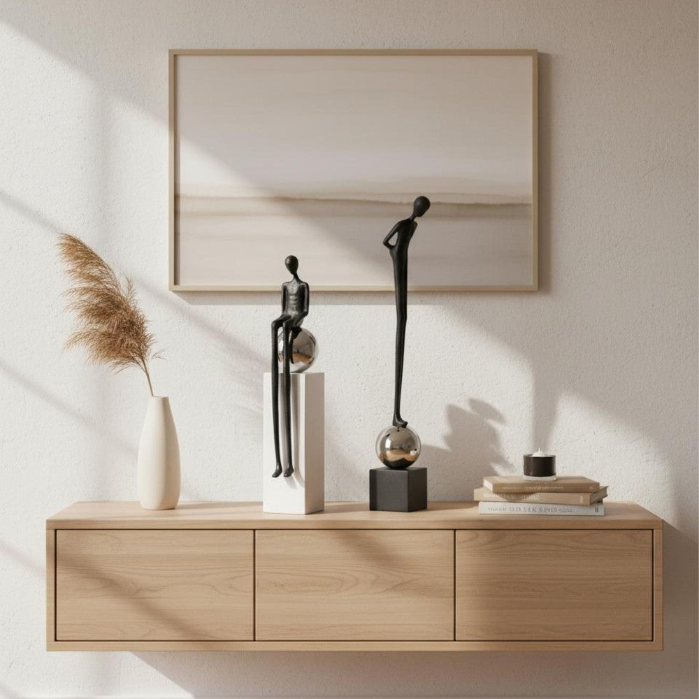 Black standing and sitting figure sculptures displayed on a light wood sideboard