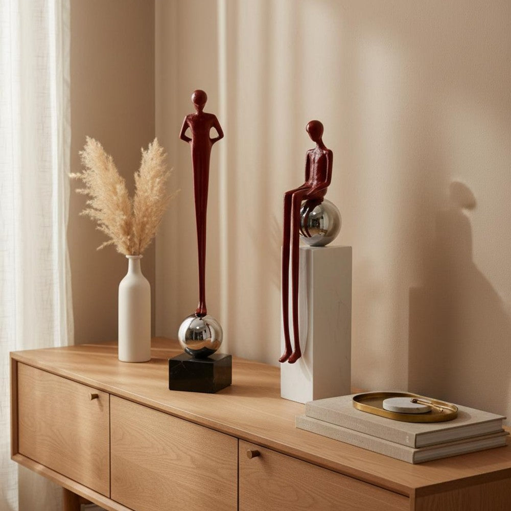 Burgundy abstract figure sculpture set styled with pampas stems on a wooden console