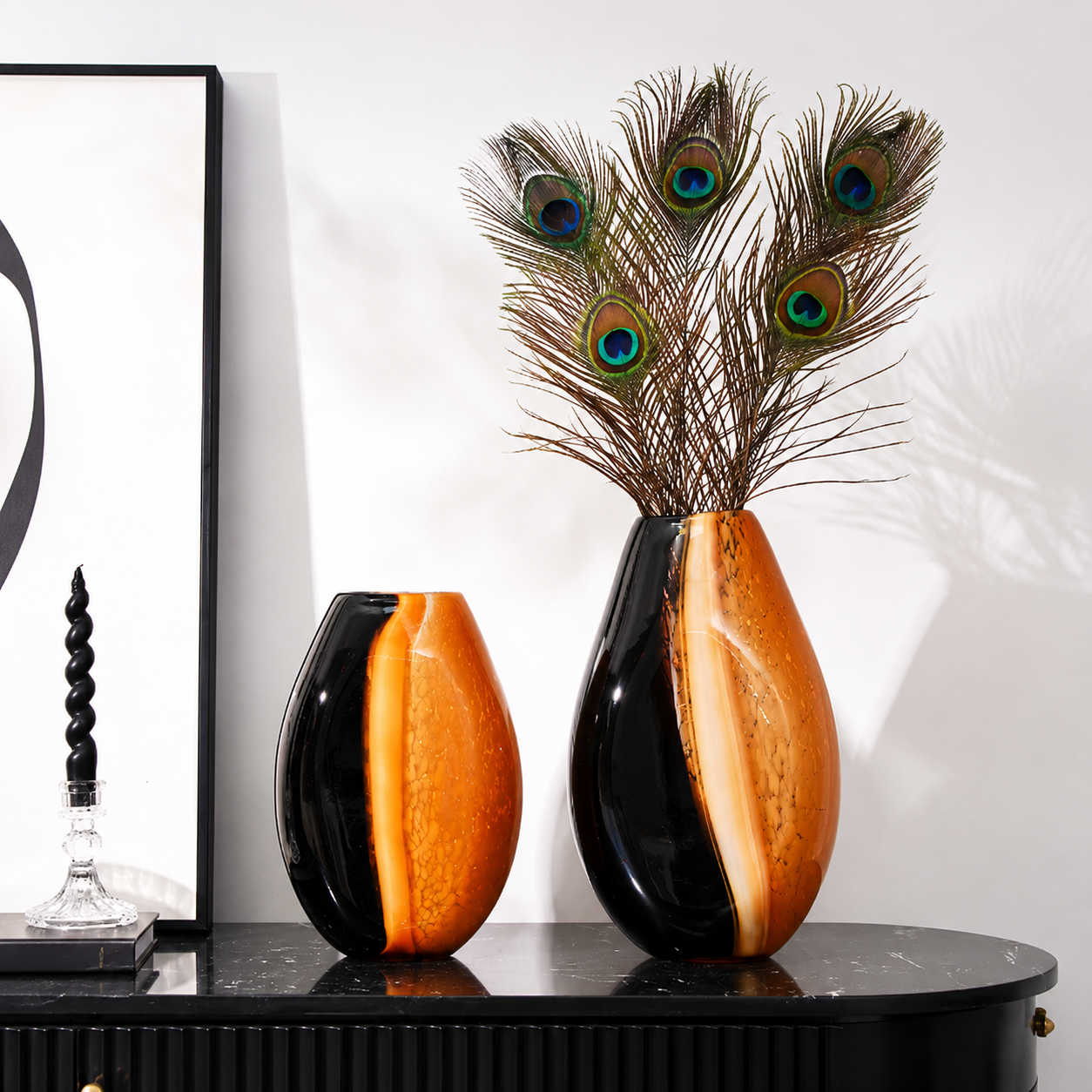 Two amber and black hand blown glass vases styled with decorative peacock feathers
