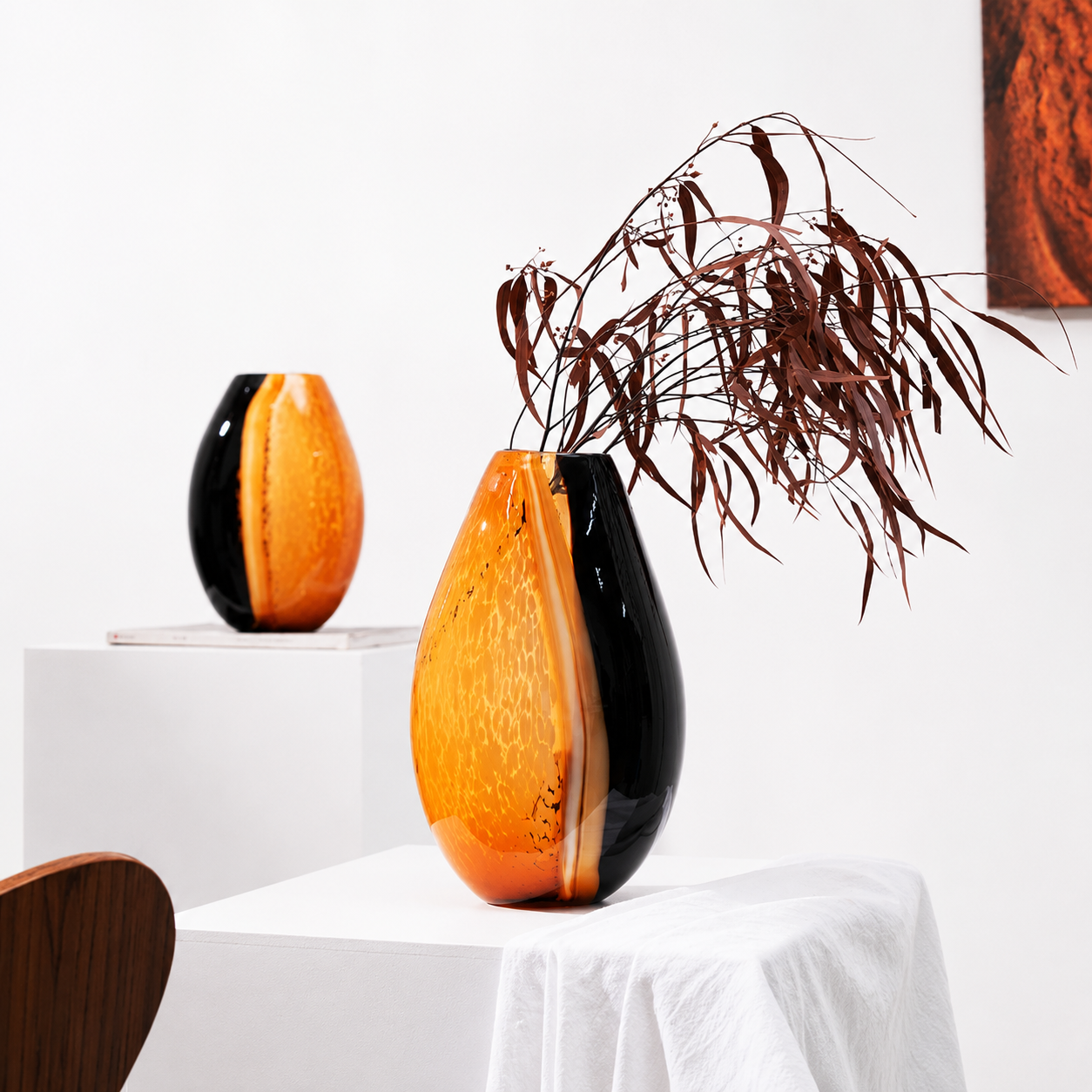Amber and black hand blown glass vase displayed with dried foliage in a bright modern interior