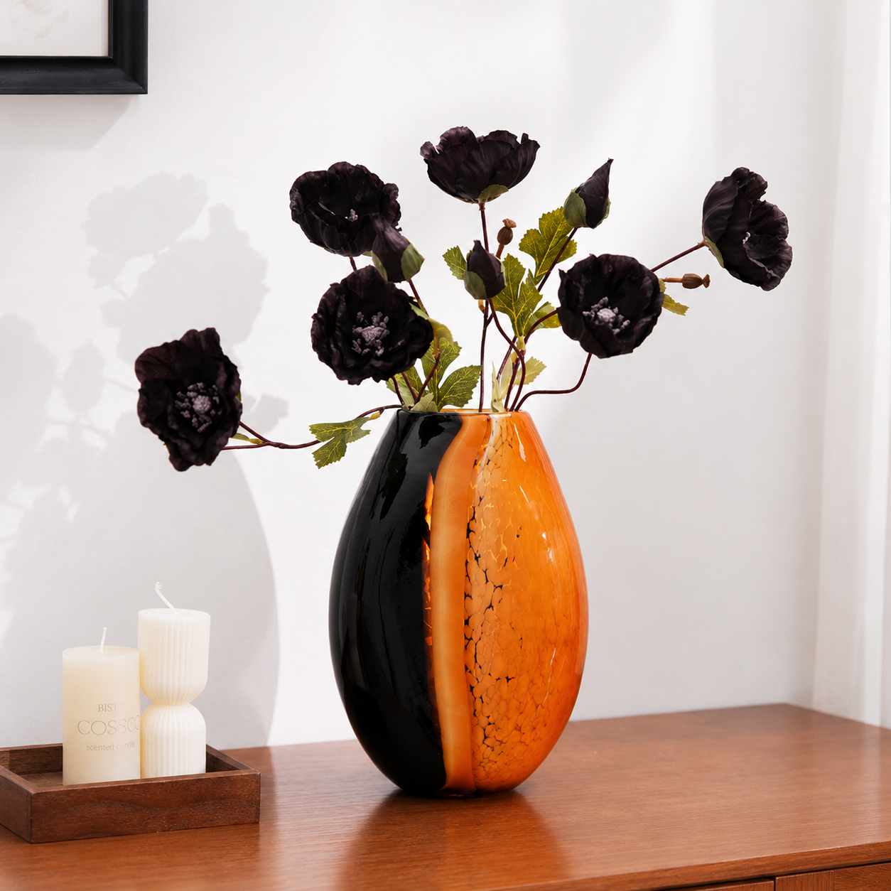 Modern amber and black glass vase arranged with artificial black flowers