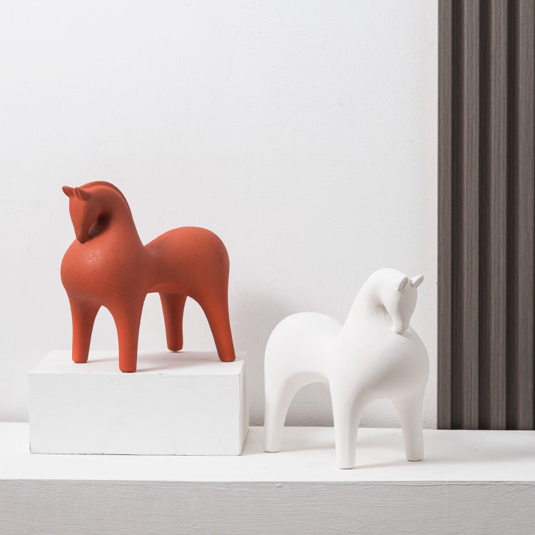 Red and white horse-shaped sculptures on a white surface with a gray curtain in the background