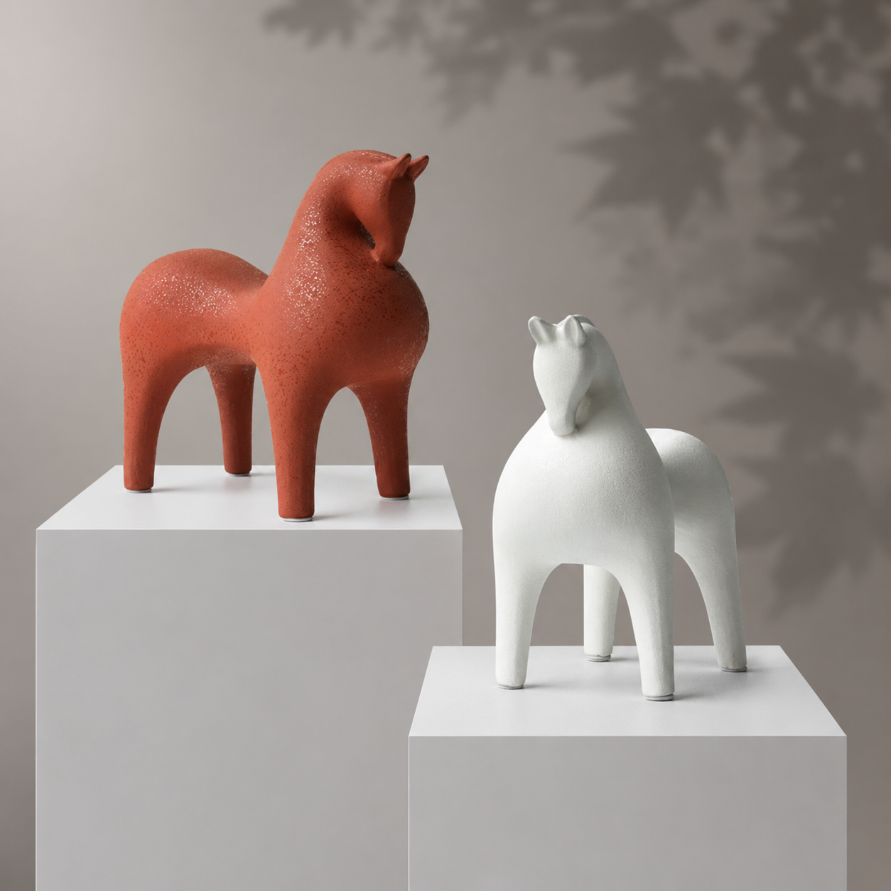 Red and white horse sculptures on white plinths against a neutral background