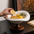 Modern white ceramic pedestal centerpiece bowl with wood base styled with fresh lemons