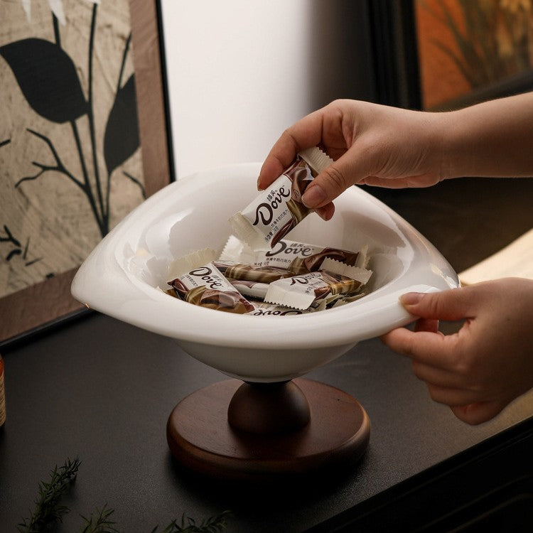 White ceramic pedestal bowl styled with wrapped treats on a contemporary table