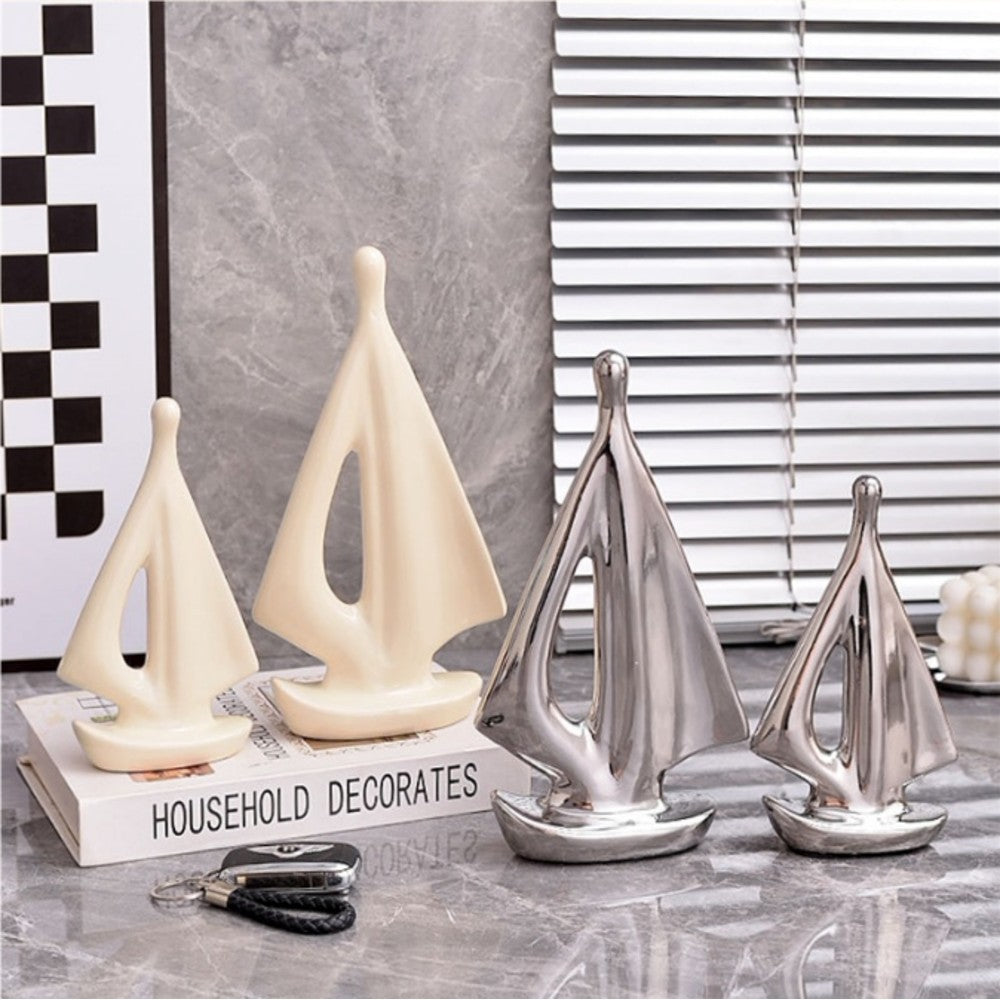 Modern ceramic sailboat sculptures in cream and silver displayed on a marble surface