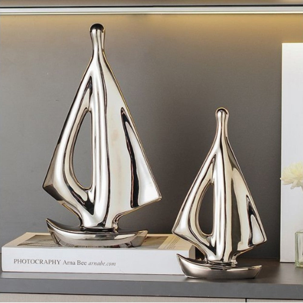 Silver ceramic sailboat sculpture set displayed in a modern interior