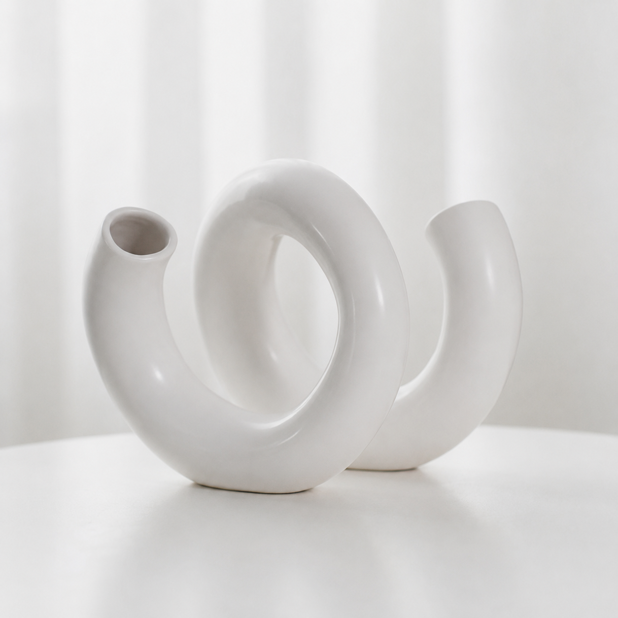 White modern loop ceramic decorative vase on a white surface