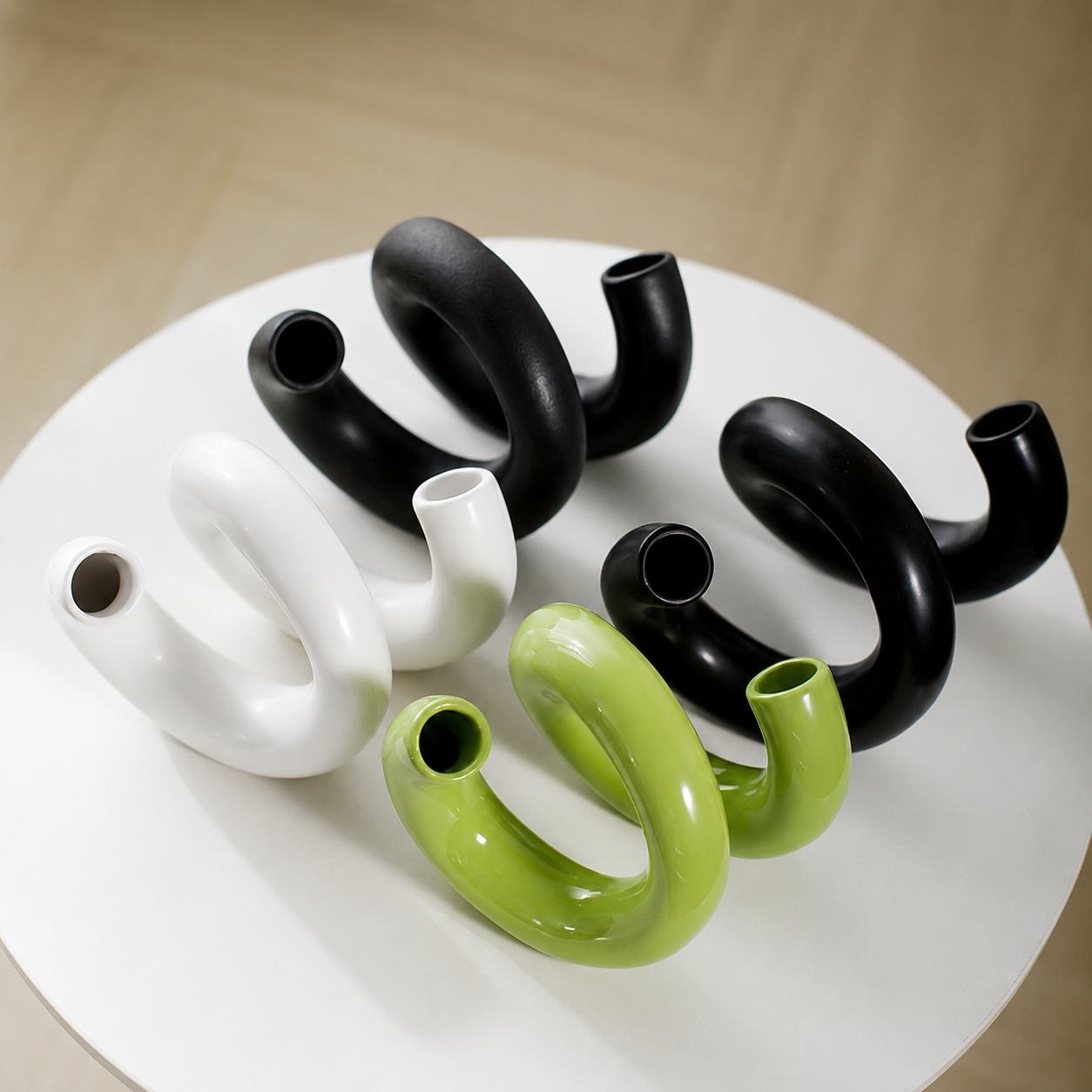 Black white and green loop ceramic vases displayed on a round table