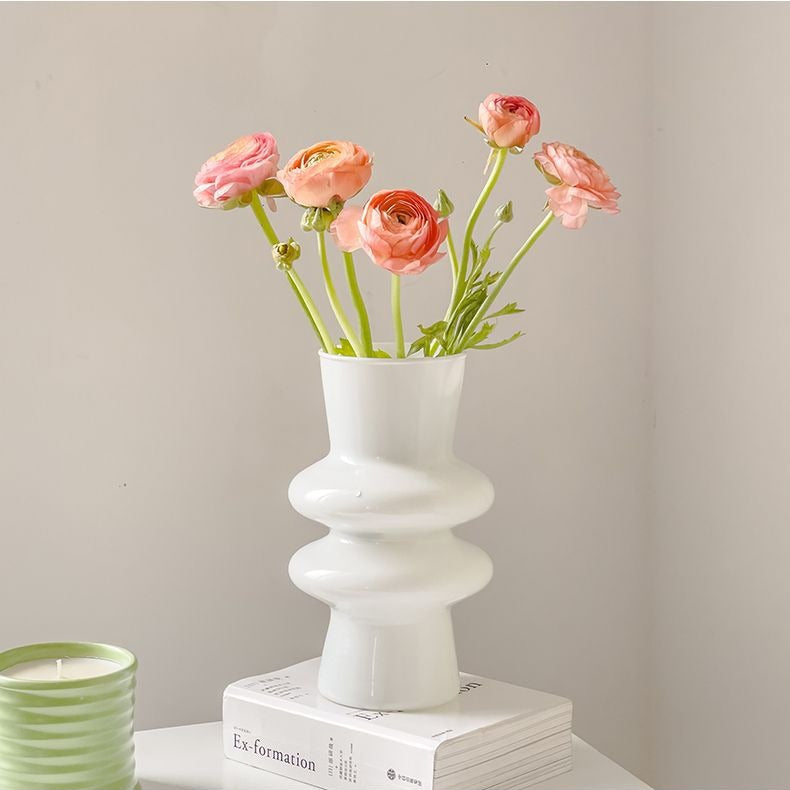 White sculptural glass vase styled with coral flowers in a modern interior