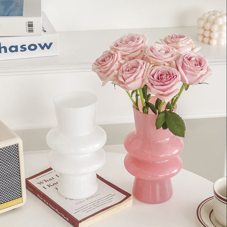 White and pink sculptural glass flower vases displayed with pink blooms and books