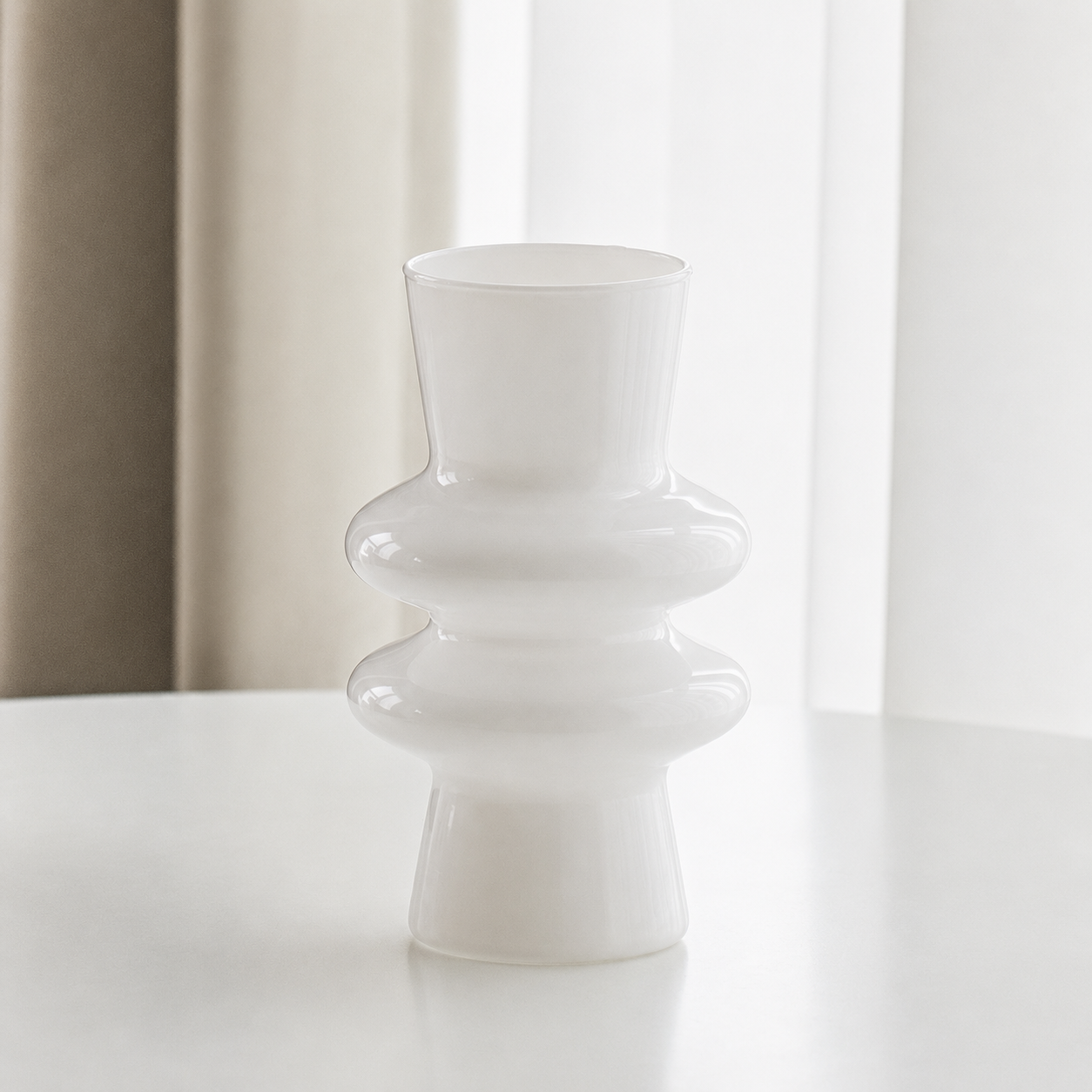 White modern sculptural glass flower vase on a white table